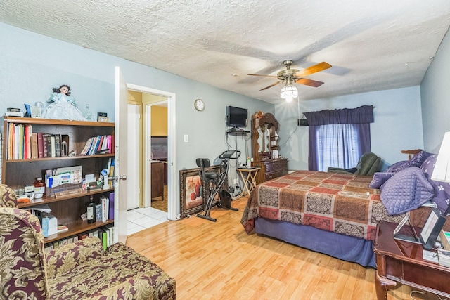 bedroom featuring a ceiling fan, a textured ceiling, and wood finished floors