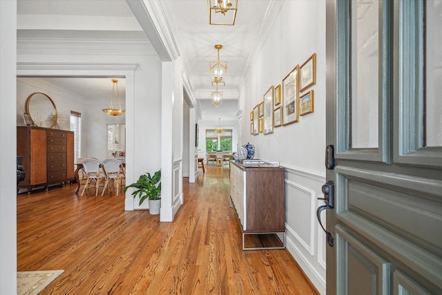 4122 University Blvd, Houston, TX 77005 - foyer featuring crown molding, a notable chandelier, a decorative wall, light wood-style flooring, and a wainscoted wall