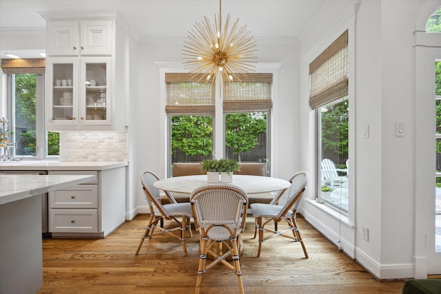 4122 University Blvd, Houston, TX 77005 - dining room featuring crown molding, light wood-style floors, a notable chandelier, and a healthy amount of sunlight
