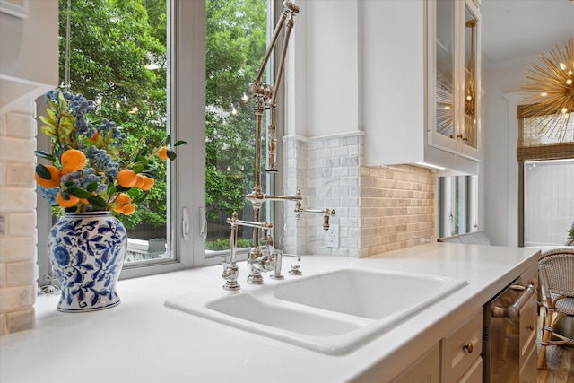 4122 University Blvd, Houston, TX 77005 - room details featuring decorative backsplash, dishwasher, light countertops, a sink, and glass insert cabinets