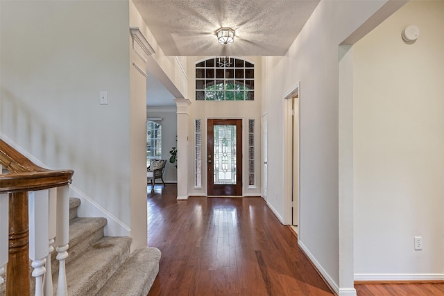 foyer featuring baseboards, wood finished floors, and stairway
