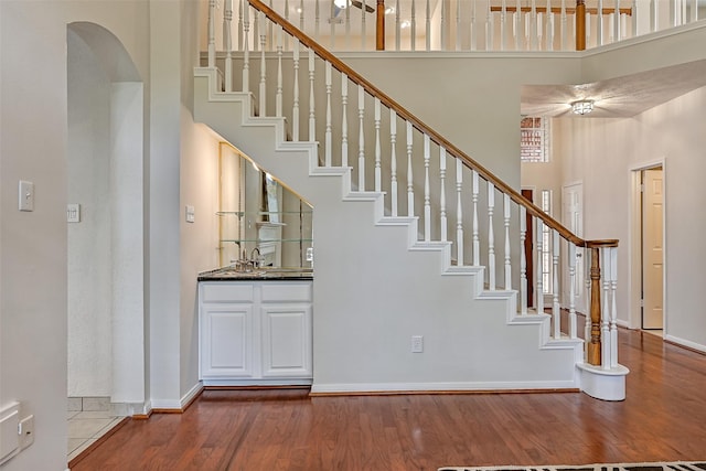 4319 Island Hills Dr, Pasadena, TX 77059 - stairs with a towering ceiling, wood finished floors, baseboards, arched walkways, and wet bar