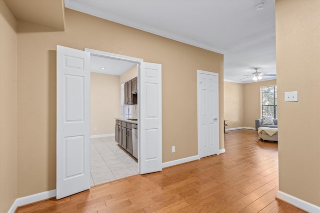 unfurnished room featuring a ceiling fan, baseboards, and light wood-style flooring