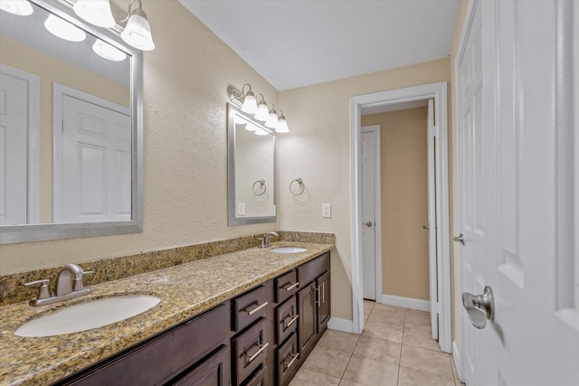 full bath featuring baseboards, double vanity, tile patterned floors, and a sink