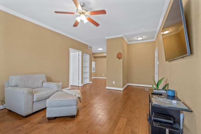 sitting room featuring ceiling fan, visible vents, crown molding, baseboards, and light wood-style floors