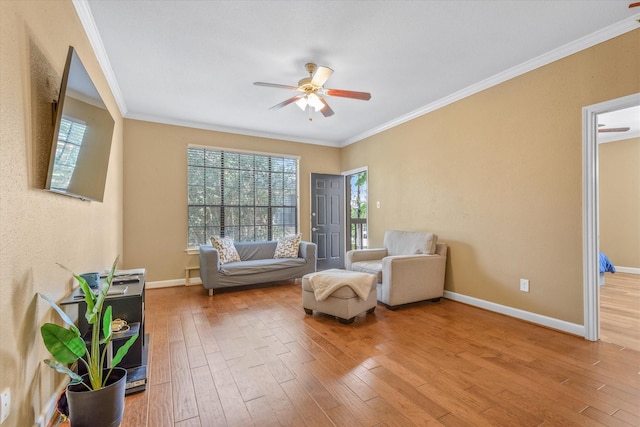 sitting room featuring crown molding, baseboards, ceiling fan, and wood-type flooring