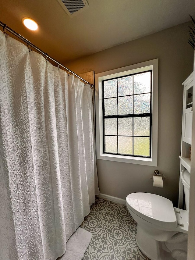 bathroom with visible vents, tile patterned floors, a healthy amount of sunlight, and toilet