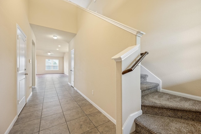 stairs with tile patterned floors, ceiling fan, and baseboards