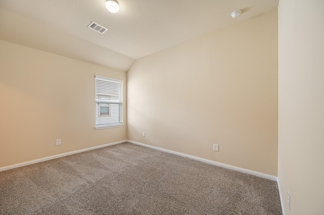 carpeted empty room featuring baseboards, visible vents, and vaulted ceiling