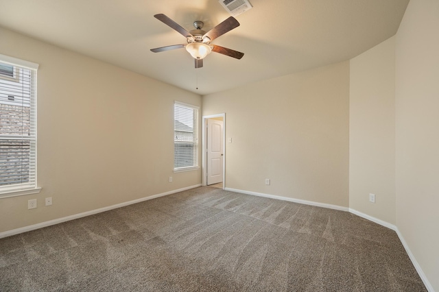 carpeted spare room featuring visible vents, baseboards, and ceiling fan