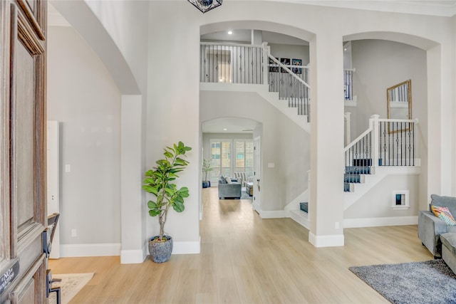 foyer entrance with baseboards, stairs, a towering ceiling, and wood finished floors