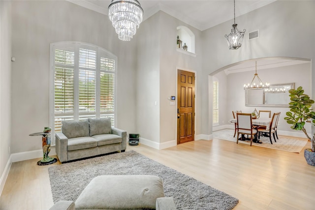 living area with an inviting chandelier, arched walkways, crown molding, and visible vents