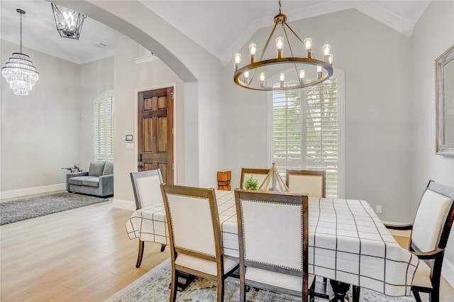 dining space with crown molding, arched walkways, wood finished floors, baseboards, and a chandelier