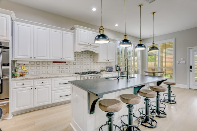 kitchen featuring light wood-type flooring, a sink, white cabinets, and stainless steel gas stovetop