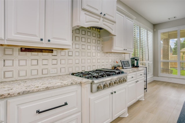 kitchen with stainless steel gas cooktop, white cabinetry, baseboards, tasteful backsplash, and visible vents