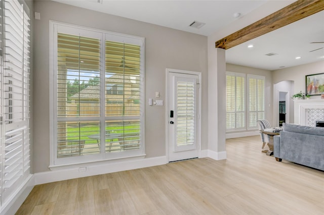 foyer entrance with baseboards, wood finished floors, and visible vents