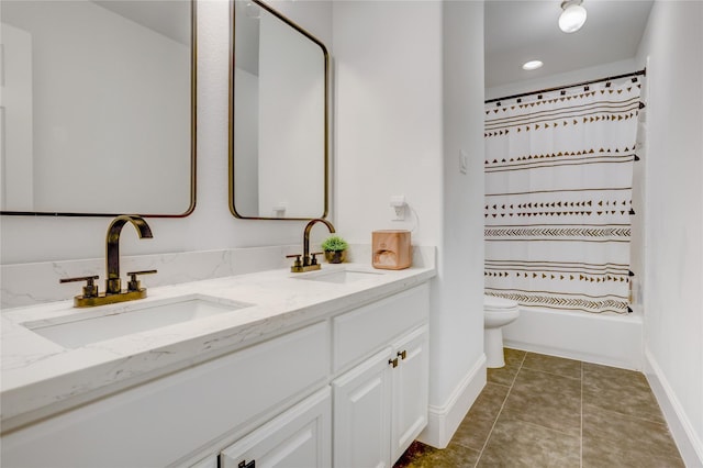 bathroom with baseboards, double vanity, toilet, and a sink