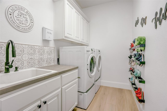 laundry room with baseboards, light wood-style floors, separate washer and dryer, a sink, and cabinet space