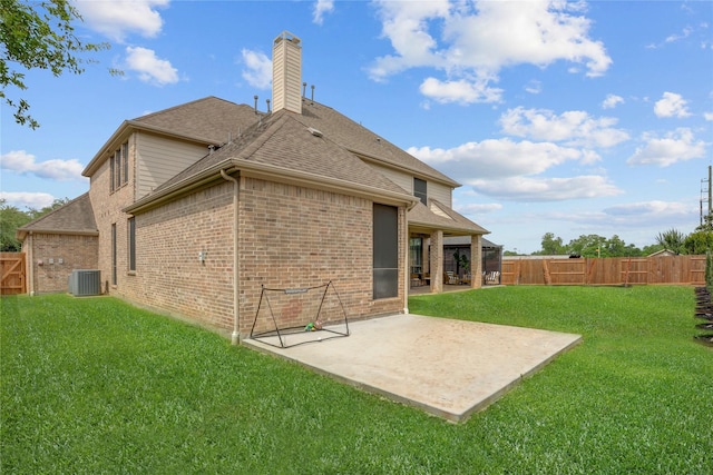 back of property featuring a shingled roof, brick siding, central AC unit, a patio area, and a yard
