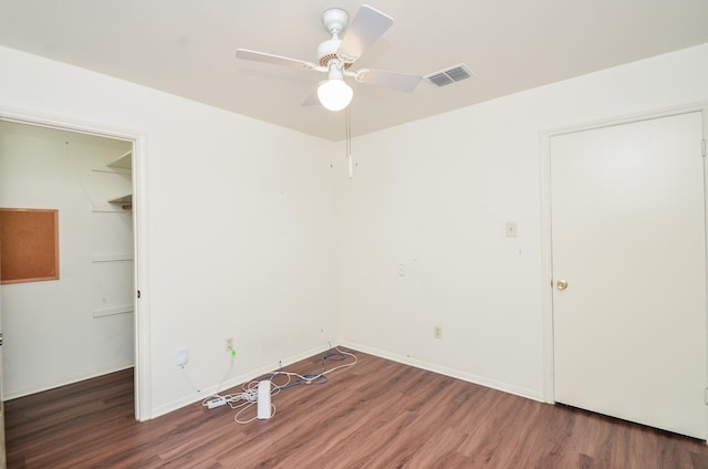 unfurnished bedroom featuring a walk in closet, visible vents, wood finished floors, and a closet