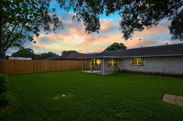 back of house featuring a lawn, brick siding, a fenced backyard, and a patio area