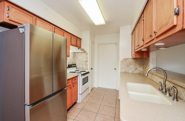 kitchen with freestanding refrigerator, white electric range, under cabinet range hood, tasteful backsplash, and a sink