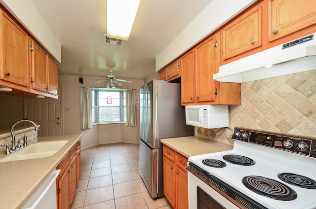 kitchen featuring a sink, white appliances, light countertops, under cabinet range hood, and visible vents