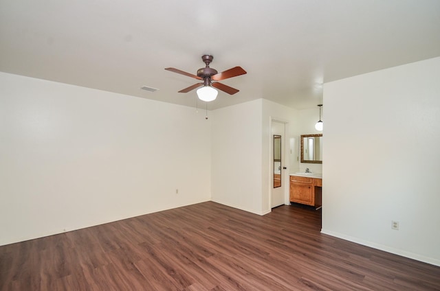 empty room with ceiling fan, visible vents, a sink, baseboards, and dark wood-style floors