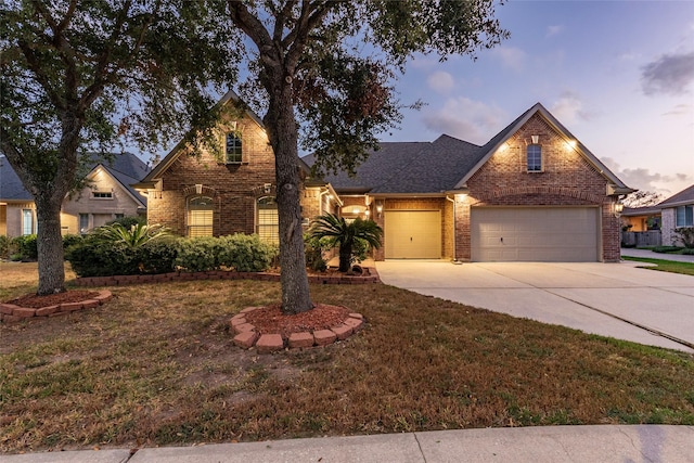 traditional-style home featuring brick siding, a garage, a yard, and concrete driveway