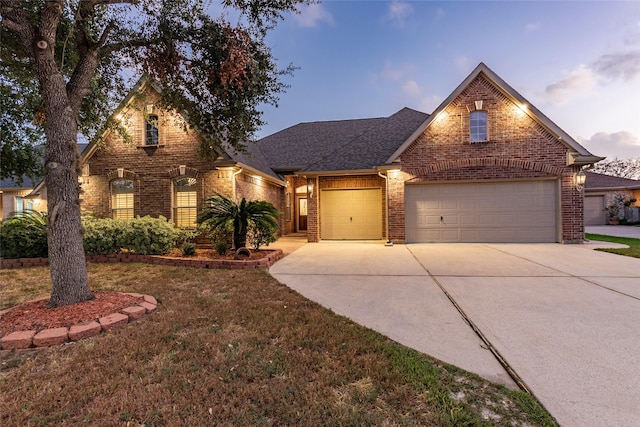 traditional home featuring brick siding, an attached garage, driveway, and a front lawn