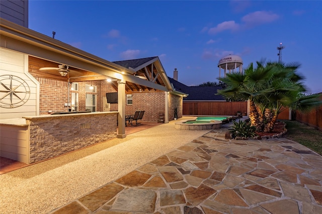 view of patio / terrace featuring an in ground hot tub, a bar, and a fenced backyard