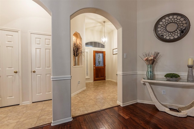 foyer entrance featuring arched walkways, baseboards, and hardwood / wood-style flooring