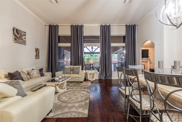 living area with arched walkways, ornamental molding, wood-type flooring, and a chandelier