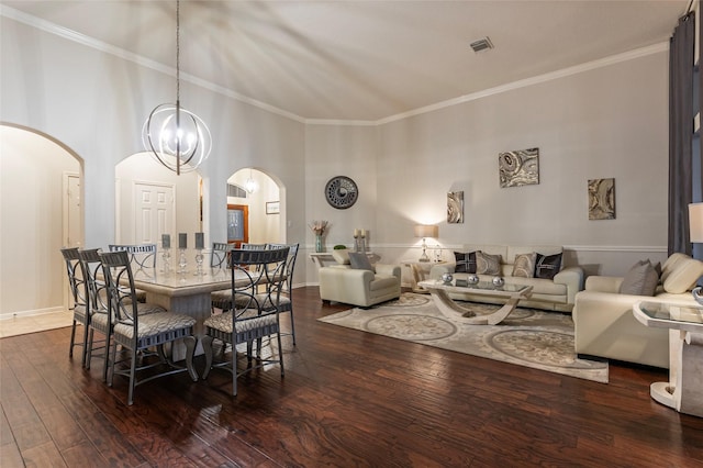 dining area with crown molding, arched walkways, a high ceiling, and hardwood / wood-style flooring