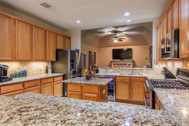 kitchen with ceiling fan, visible vents, appliances with stainless steel finishes, a sink, and light stone counters
