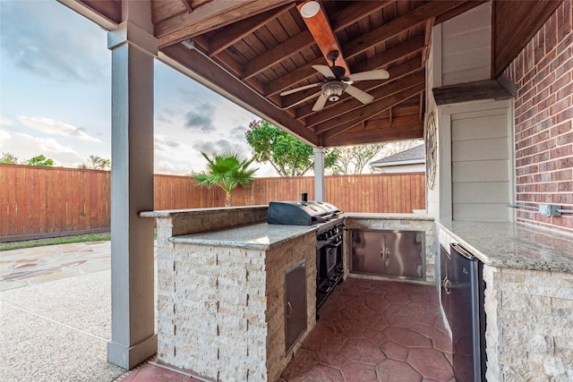 view of patio / terrace featuring a fenced backyard, ceiling fan, a grill, and exterior kitchen