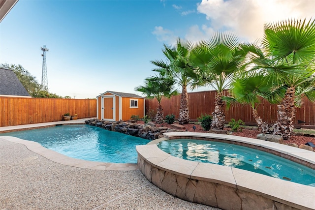 view of pool featuring an outdoor structure, a fenced backyard, a shed, a fenced in pool, and an in ground hot tub