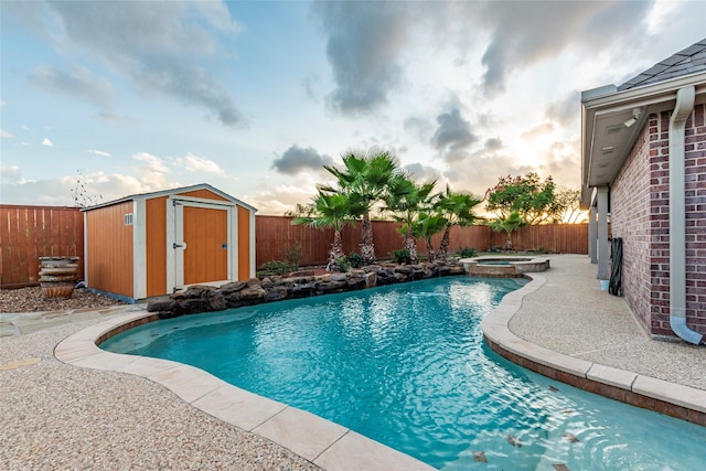 view of pool featuring a fenced backyard, a patio area, a shed, and an outbuilding