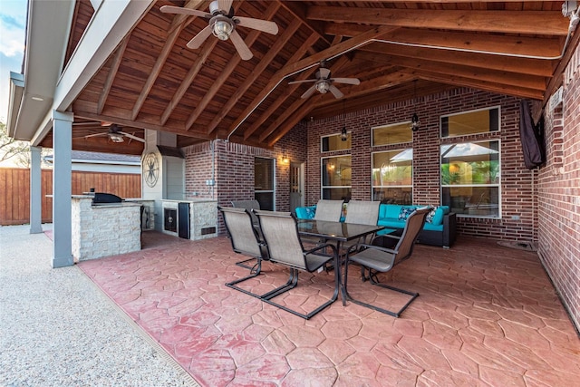 view of patio / terrace featuring ceiling fan, exterior kitchen, outdoor dining space, and fence
