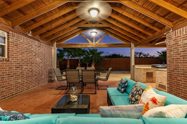 patio terrace at dusk featuring an outdoor living space, outdoor dining area, fence, and a gazebo