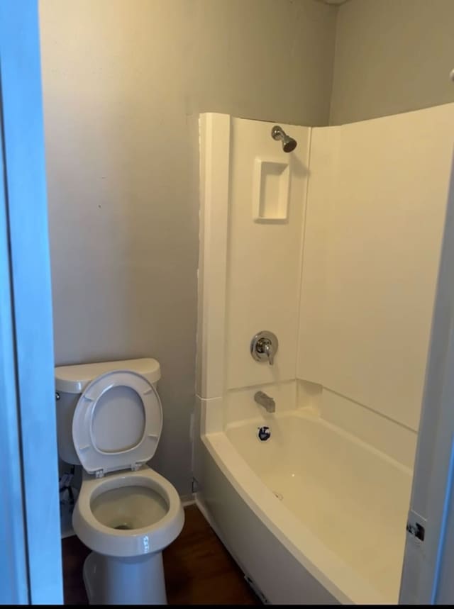 bathroom with shower / bathtub combination, baseboards, toilet, and wood finished floors