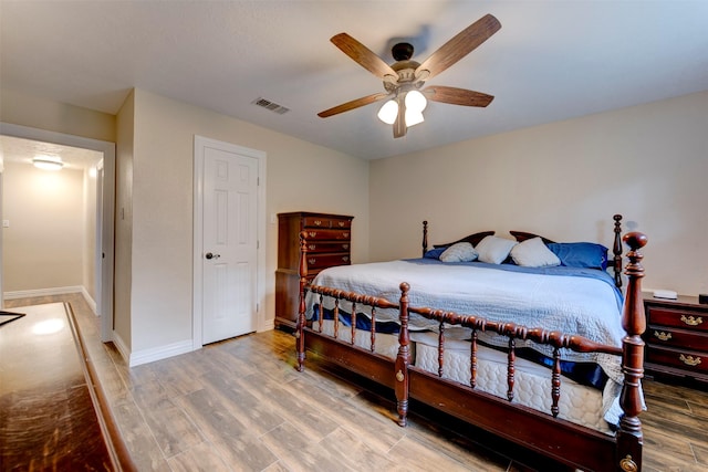 bedroom featuring baseboards, ceiling fan, wood finished floors, and visible vents