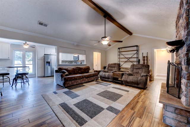 living area with light wood-style floors, ceiling fan, a textured ceiling, and visible vents