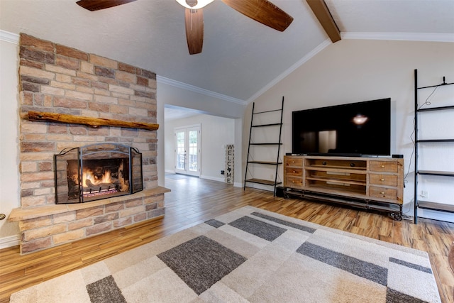 unfurnished living room featuring lofted ceiling with beams, a fireplace, a ceiling fan, wood finished floors, and ornamental molding