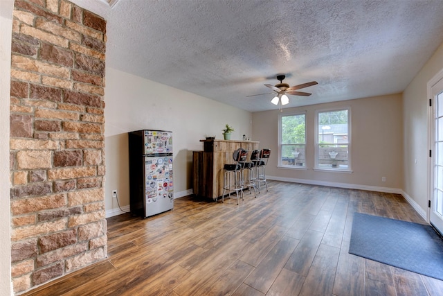 office featuring baseboards, a ceiling fan, a textured ceiling, and wood finished floors