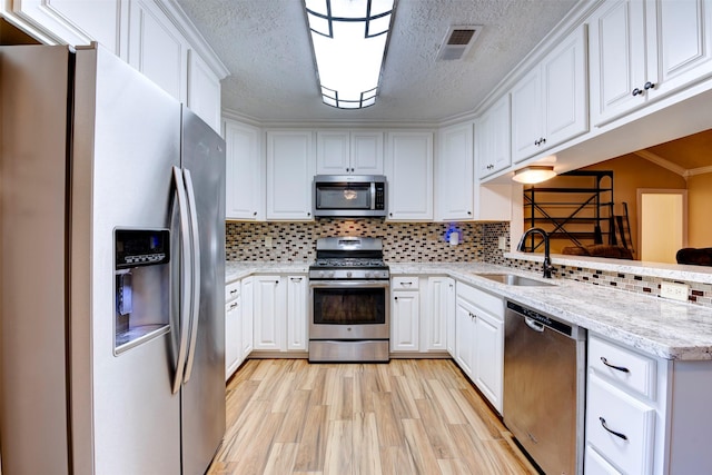 kitchen with visible vents, appliances with stainless steel finishes, light wood-style flooring, a sink, and white cabinetry