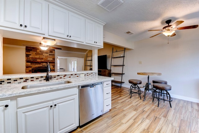 kitchen with a sink, a ceiling fan, backsplash, stainless steel dishwasher, and visible vents