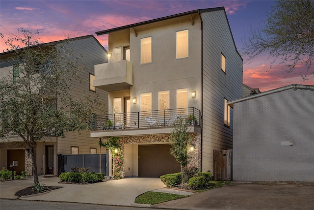 view of front of home featuring a garage, stucco siding, a balcony, and driveway
