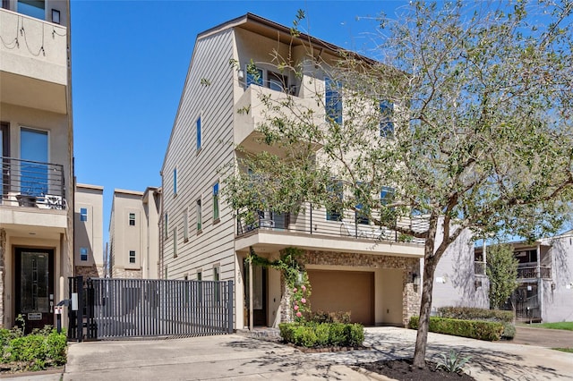 view of property featuring a gate, stucco siding, an attached garage, and driveway