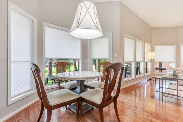 dining space with baseboards, ornamental molding, and light wood-type flooring
